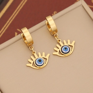 Detailed macro shot of golden Evil Eye dangle earrings on a jewelry box background