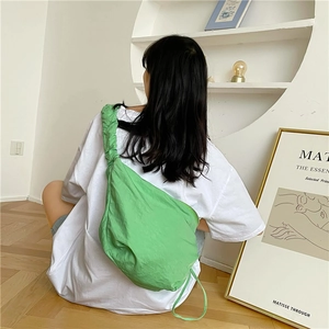 Dettaglio di una borsa in nylon verde vivace con tracolla a pieghe dal design esclusivo