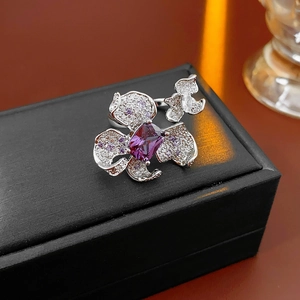 Detailed close-up of a flower-shaped ring with purple stones on a black jewelry box