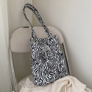 Detail of the zebra print canvas tote bag with Augur label hanging on a white chair