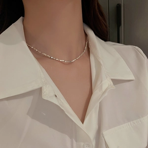 Close-up of minimalist irregular silver-tone geometric necklace on a white shirt