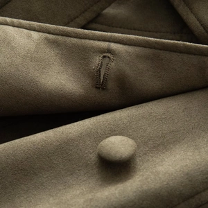 Macro detail of matching olive green suede fabric buttons and reinforced buttonholes
