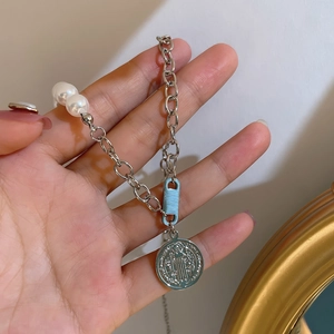 Detail of silver chain with white pearls and a St. Benedict pendant held in hand