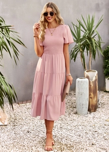 Detail of pink smocked bodice and tiered midi skirt on a summer vacation dress