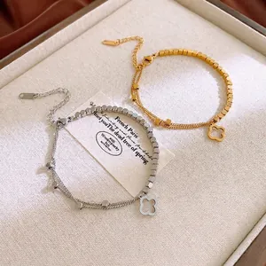 Elegant gold and silver stainless steel flower bracelets with clover charms on a tray