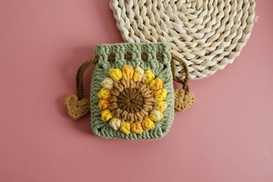 Close-up of handmade crochet sunflower pouch in green yarn with a brown drawstring