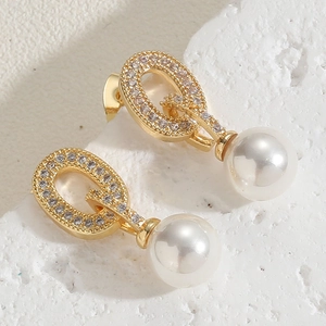 Macro shot of gold G-shaped drop earring with sparkling pavé crystals and white pearl