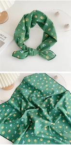 Detail of green floral square scarf with silk-like texture and knotted bowtie style