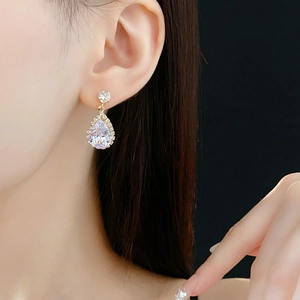 Gros plan sur des boucles d'oreilles goutte d'or avec oxydes de zirconium sur un modèle