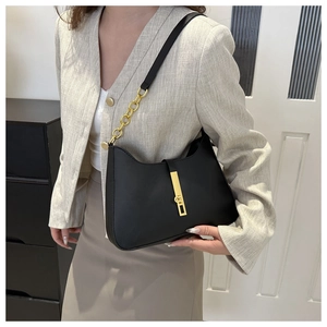 Detail of black matte leather shoulder bag with gold metal buckle and chain strap