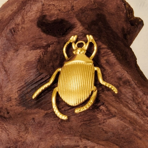 Polished golden beetle pendant in 304 stainless steel displayed on a wood block