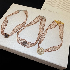 Detail of vintage brown lace chokers with heart, floral, and sun pendants with pearls