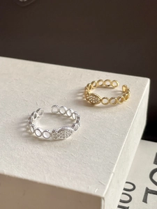 Detail of silver and gold fish rings with cubic zirconia on a minimalist platform