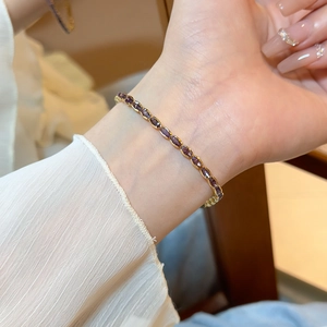 Detail of elegant gold bracelet with oval purple zircon stones on female wrist