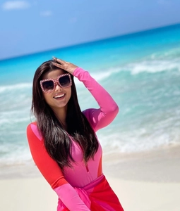 Detail of pink long-sleeve swimsuit with high-neck zipper on a sunny beach background