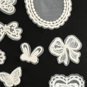 Cream white embroidered lace patches featuring butterflies and bows on black background
