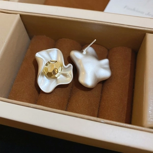 Detail of flower-shaped stud earrings with gold bead center in a jewelry box