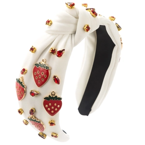 Détail d'un bandeau blanc à nœuds orné de breloques fraises et de pierres précieuses rouges
