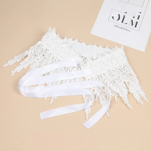 Detail of white lace waist belt with delicate leaf embroidery and satin ribbon ties