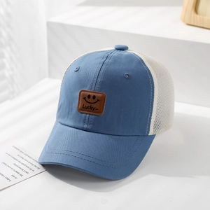 Detail of blue and white mesh baseball cap featuring a leather smiley face lucky patch