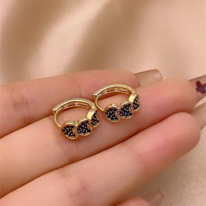 Detailed close-up of gold hoop earrings with three blue pavé zircon hearts on satin