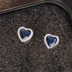 Detailed close-up of heart-shaped blue sapphire stud earrings in silver bezel setting