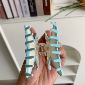 Macro view of blue and white acrylic butterfly hair claw clip with strawberry detail
