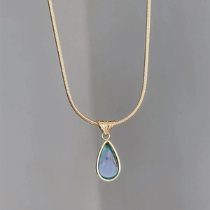 Detailed macro of a gold snake chain with a teardrop blue opal pendant for women
