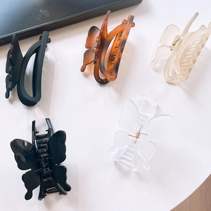 Elegant butterfly hair clips set in matte black, amber tortoiseshell and clear finishes