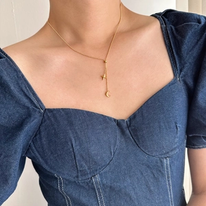 Detail of gold star and crescent moon Y-shaped tassel necklace on model neck