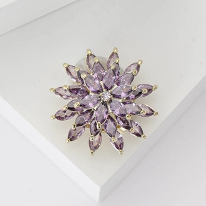 Close-up of golden flower brooch with marquise purple zircons and central crystal detail
