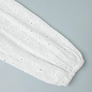 Detail of white cotton sleeve featuring delicate eyelet embroidery and elastic cuffs