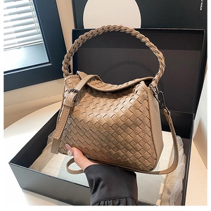 Close-up of khaki hand-woven handbag with square texture and detachable shoulder strap