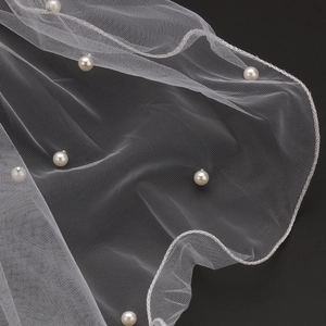 Elegant white bridal veil with handcrafted pearls and fine mesh detail on black background
