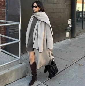 Full-length outdoor street view of a beige wool coat with a matching scarf and high boots