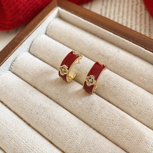 Detailed close-up of retro red enamel clover earrings with gold beaded edges in a box