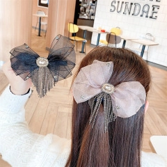 Close-up of elegant mesh bow hair clips with long metal tassels and sparkling rhinestones
