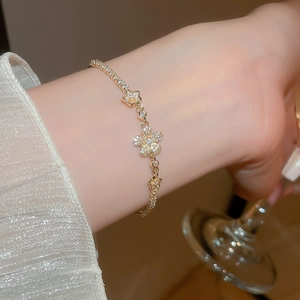 Close-up of sparkling zircon flower bracelet on wrist holding a glass, luxury gold finish
