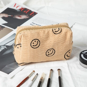 Macro detail of beige corduroy pouch with embroidered smileys and silver zipper head