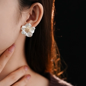Close-up of zircon flower stud earrings with artificial pearls worn by a model
