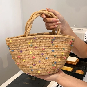 Cute woven straw tote bag with colorful pom poms and braided handles for summer style