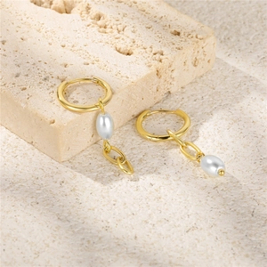 Detail of S925 sterling silver asymmetrical earrings with pearls and chain on stone