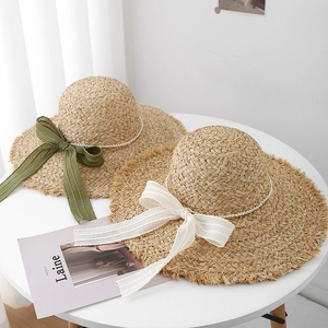 Cappello in paglia di rafia a tesa larga con catena di perle e fiocco per vacanze estive