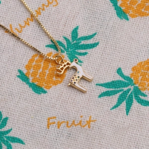 Gold plated deer pendant necklace with colorful enamel on a decorative fabric background