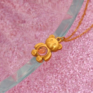 Y2K minimalist gold bear pendant necklace with pink bead on light blue glass edge
