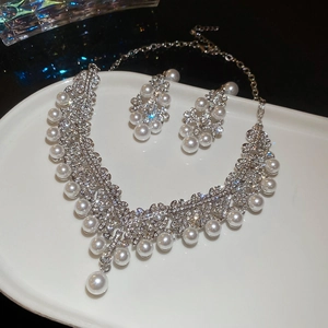 Détail d'un ensemble de bijoux fleurs en strass et perles sur un plateau de présentation