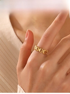 Detail of a gold plated hollow rectangular link ring worn on a finger for a modern look