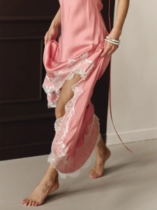 Détail de robe longue en satin rose avec dentelle blanche élégante sur la fente latérale