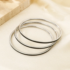Three-piece set of 3mm minimalist polished stainless steel bangles on beige fabric