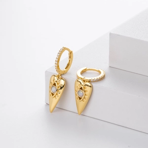Detailed shot of golden heart evil eye earrings with opal stones on a marble stand